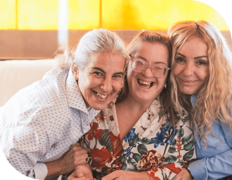 Three women smiling and embracing each other.